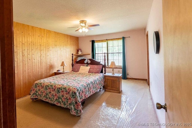bedroom featuring wooden walls, ceiling fan, carpet, and a textured ceiling