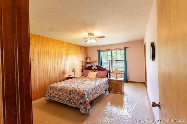 carpeted bedroom featuring wood walls, a textured ceiling, and ceiling fan