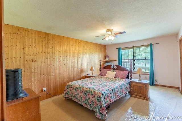 carpeted bedroom featuring wood walls, a textured ceiling, and a ceiling fan