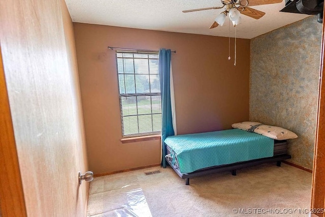 carpeted bedroom featuring visible vents, baseboards, ceiling fan, and multiple windows