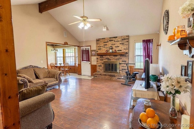 living room featuring a ceiling fan, a fireplace, beam ceiling, wood finished floors, and high vaulted ceiling