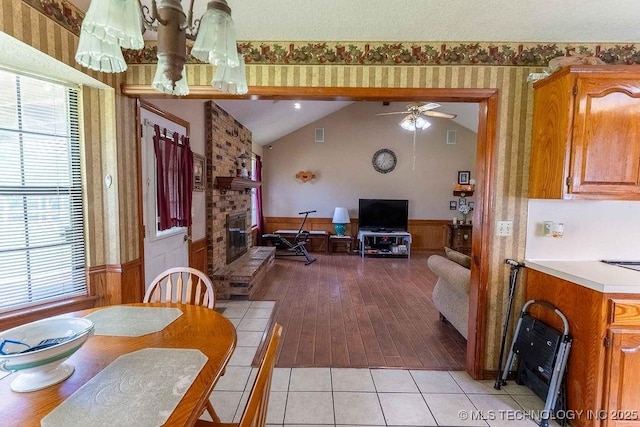 dining room featuring a brick fireplace, a wainscoted wall, and wallpapered walls