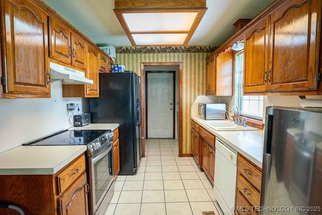 kitchen with wallpapered walls, under cabinet range hood, brown cabinets, a sink, and stainless steel appliances
