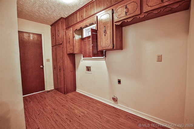 clothes washing area featuring cabinet space, hookup for a washing machine, a textured ceiling, electric dryer hookup, and wood finished floors