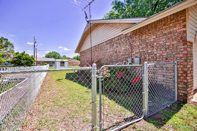 view of property exterior with brick siding, a gate, a lawn, and fence