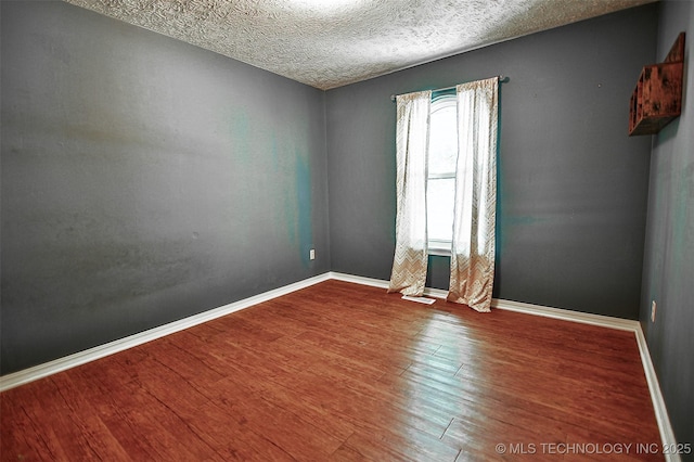 unfurnished room featuring baseboards, a textured ceiling, and wood finished floors
