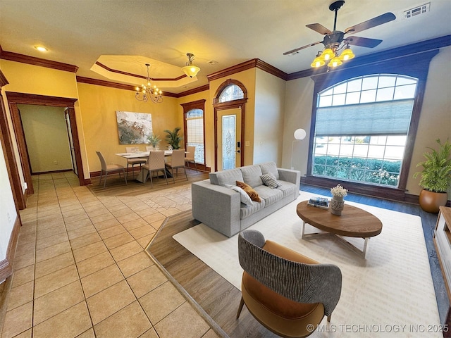 living room featuring crown molding, light tile patterned floors, a chandelier, a ceiling fan, and baseboards