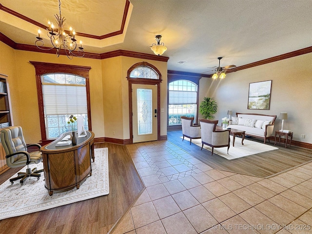 foyer featuring ornamental molding, a chandelier, baseboards, light wood finished floors, and ceiling fan