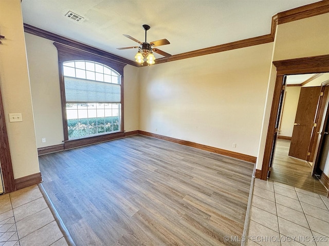 empty room featuring ornamental molding, ceiling fan, light wood finished floors, and baseboards