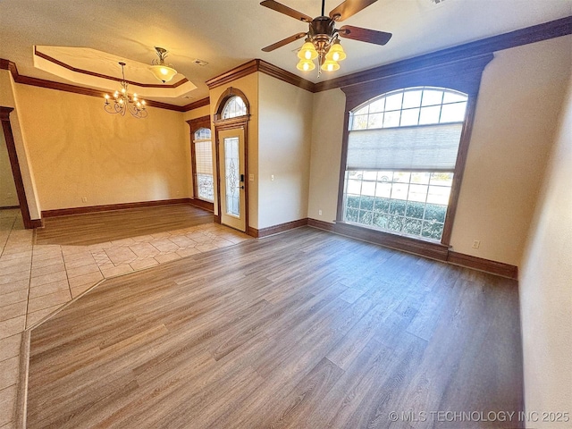 empty room with wood finished floors, crown molding, a chandelier, ceiling fan, and baseboards