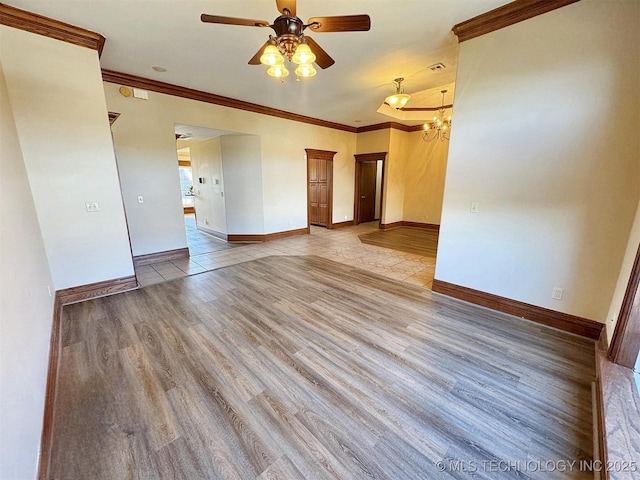 spare room featuring crown molding, a ceiling fan, baseboards, light wood-style flooring, and a chandelier