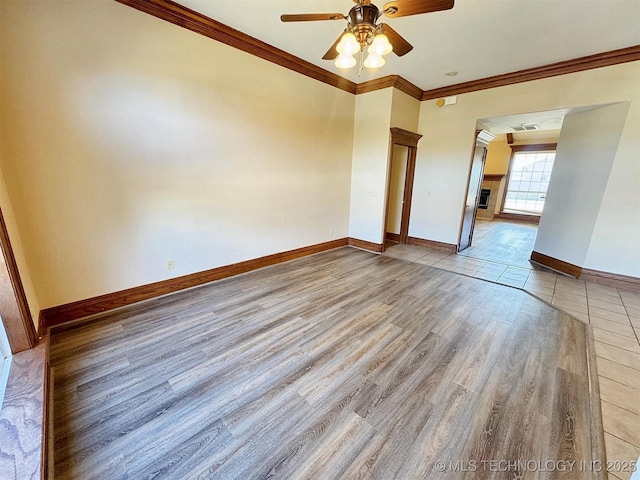 spare room with ceiling fan, wood finished floors, ornamental molding, and baseboards