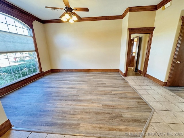 spare room featuring crown molding, healthy amount of natural light, ceiling fan, baseboards, and light wood-type flooring