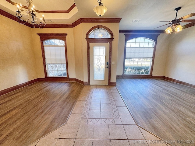 entrance foyer featuring crown molding, healthy amount of natural light, light wood-style floors, a chandelier, and a ceiling fan