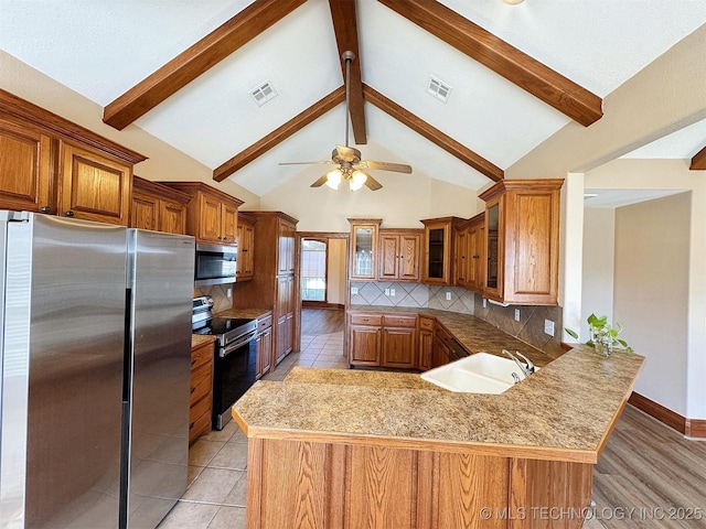 kitchen featuring appliances with stainless steel finishes, ceiling fan, brown cabinetry, decorative backsplash, and a sink