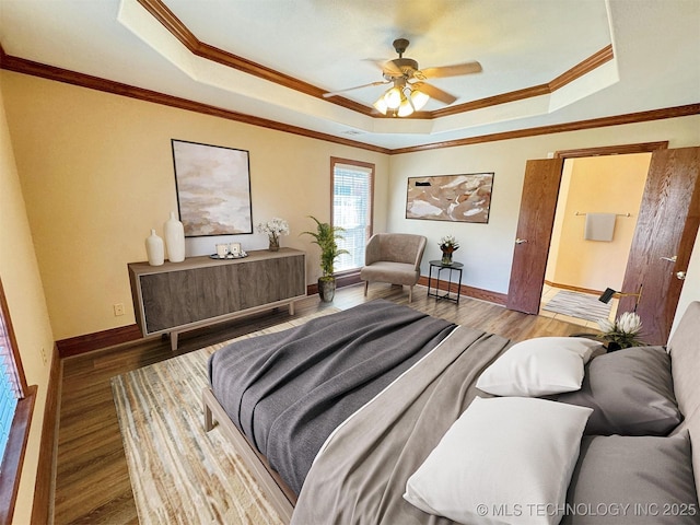 bedroom featuring a tray ceiling, crown molding, wood finished floors, and baseboards
