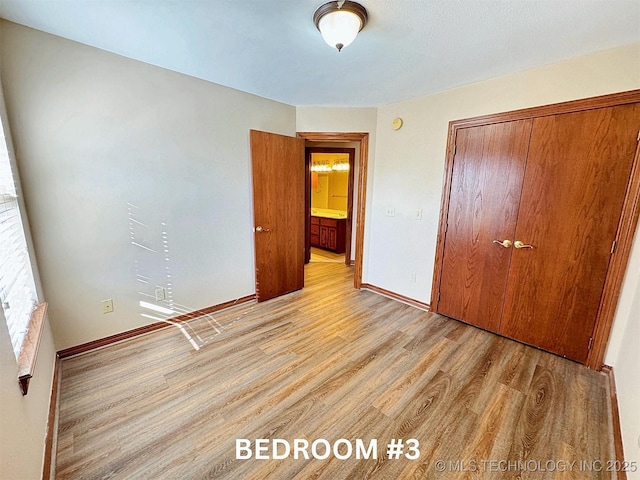 unfurnished bedroom with light wood-type flooring, a closet, and baseboards