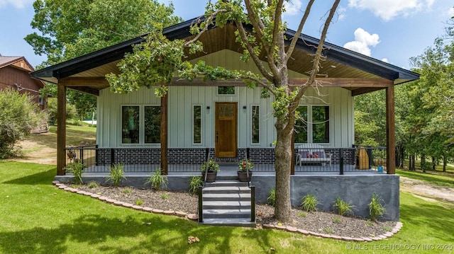 view of front facade featuring covered porch, board and batten siding, and a front yard