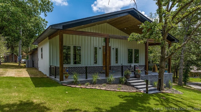 view of side of property featuring a porch, a lawn, and central AC
