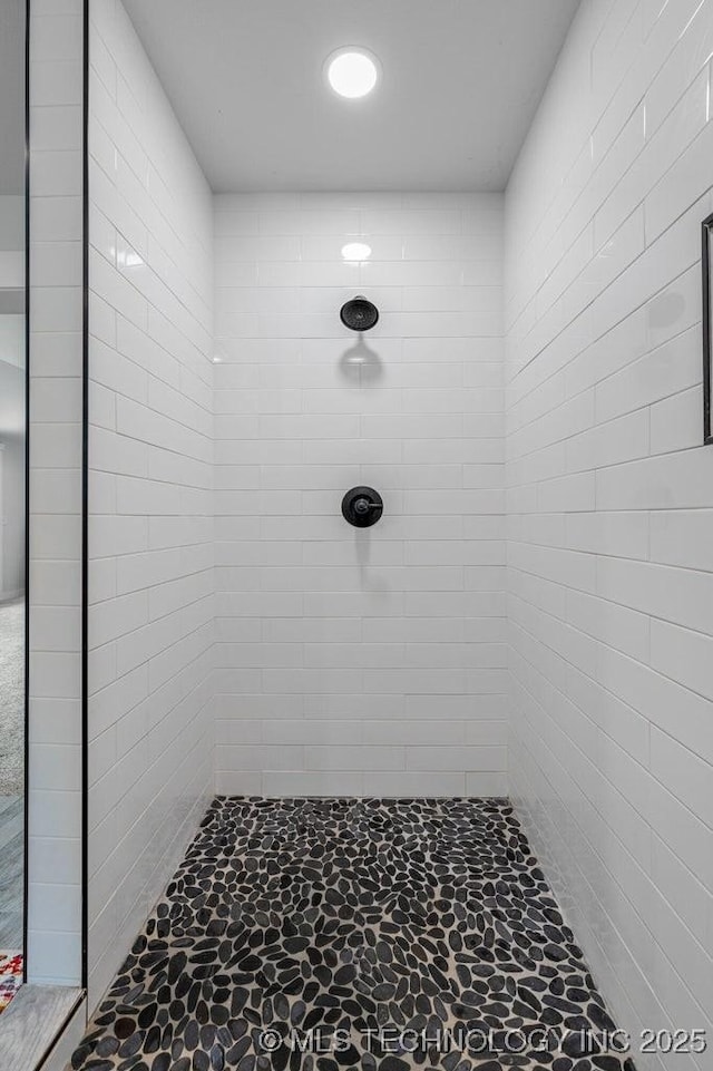 bathroom with stone flooring and a tile shower