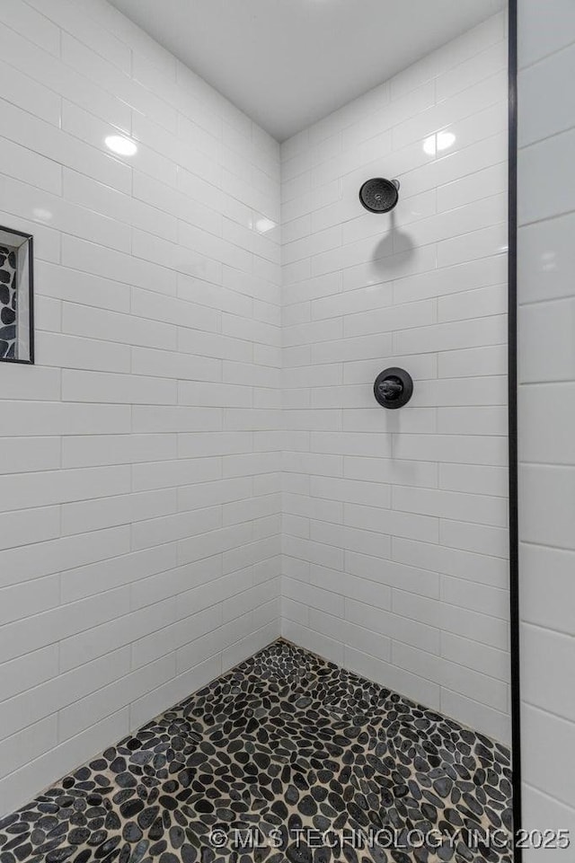 bathroom featuring a tile shower and stone finish flooring