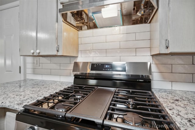 kitchen featuring gas stove, ventilation hood, light stone countertops, and tasteful backsplash