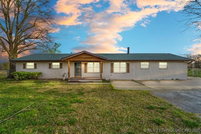 ranch-style home with concrete driveway, a front lawn, and brick siding