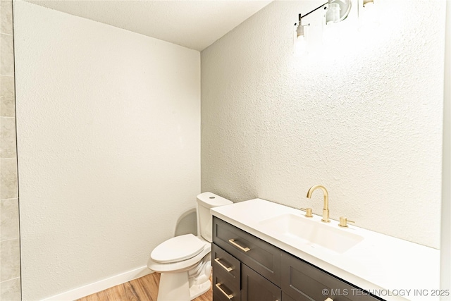 bathroom with vanity, baseboards, toilet, and wood finished floors