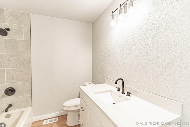 bathroom featuring visible vents, bathtub / shower combination, wood finished floors, vanity, and toilet
