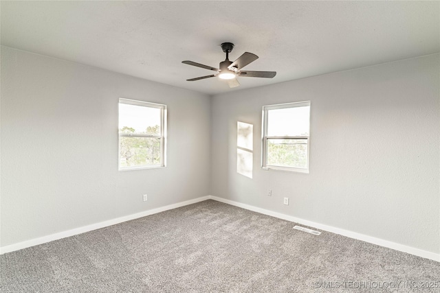 carpeted empty room featuring baseboards, plenty of natural light, a ceiling fan, and visible vents