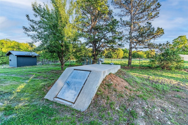 view of storm shelter with a lawn, a storage unit, an outdoor structure, and fence