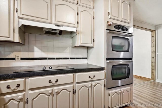 4604 Maple Dr, Sand Springs, OK 74063 - kitchen with dark countertops, stainless steel double oven, decorative backsplash, wood finished floors, and under cabinet range hood