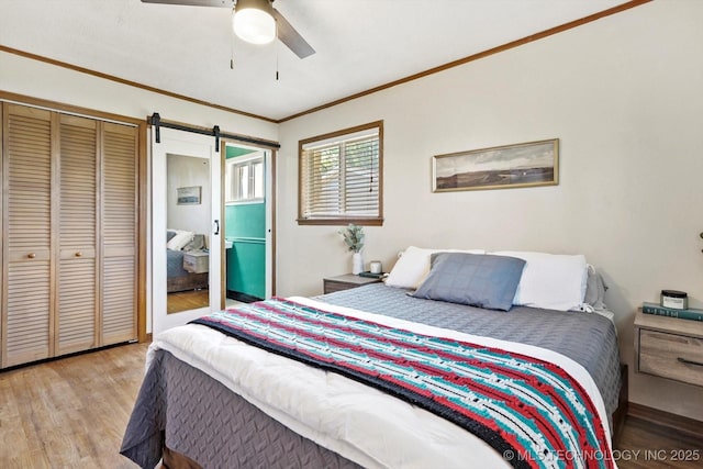 4604 Maple Dr, Sand Springs, OK 74063 - bedroom featuring crown molding, a barn door, light wood-style flooring, a ceiling fan, and a closet