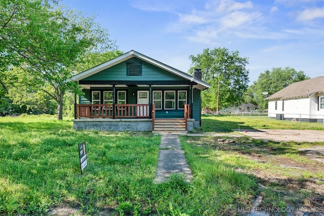 bungalow-style house with a porch, fence, and a chimney