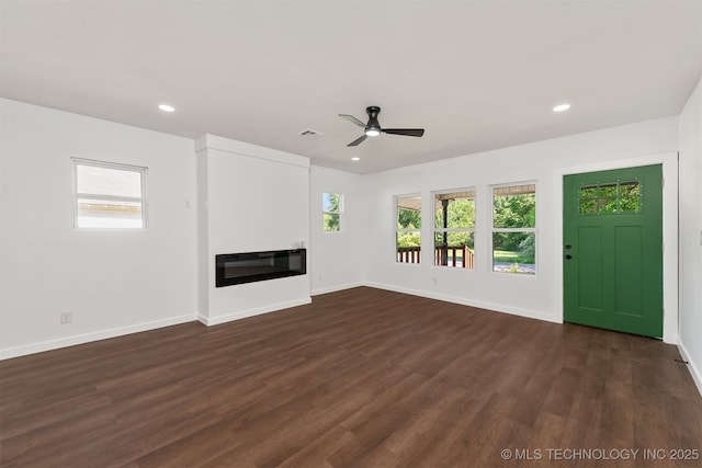 unfurnished living room with visible vents, dark wood-style flooring, a glass covered fireplace, baseboards, and ceiling fan