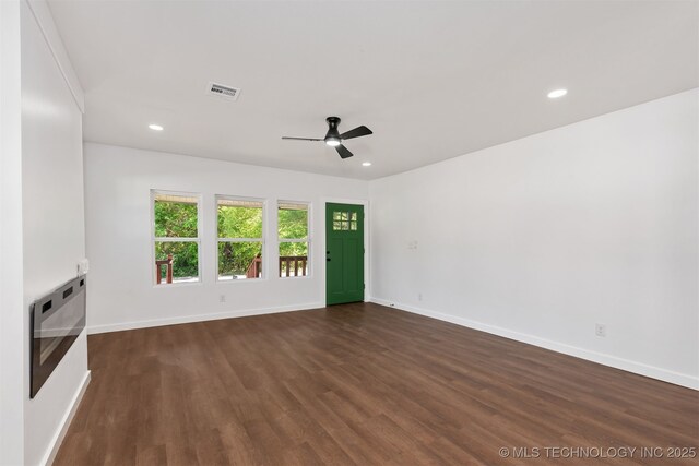 unfurnished living room with baseboards, ceiling fan, dark wood-style floors, and visible vents