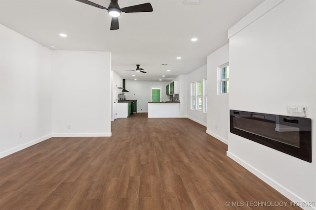 unfurnished living room featuring baseboards, ceiling fan, recessed lighting, and dark wood-type flooring
