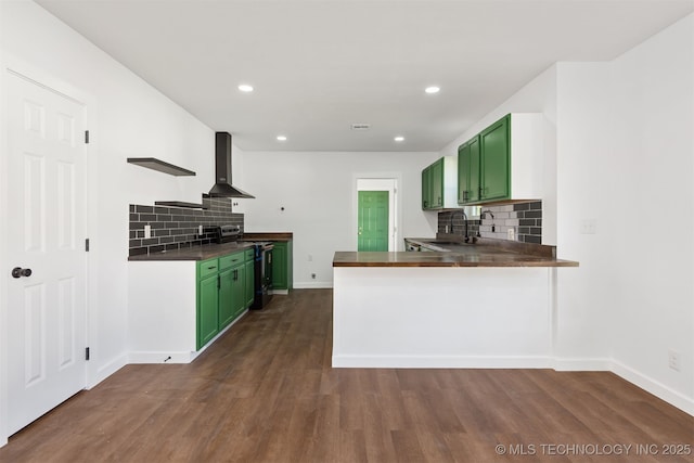 kitchen featuring green cabinetry, dark countertops, wall chimney exhaust hood, and electric stove