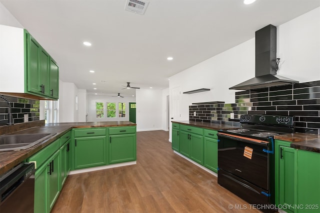 kitchen featuring visible vents, wall chimney range hood, black electric range, dishwasher, and green cabinets