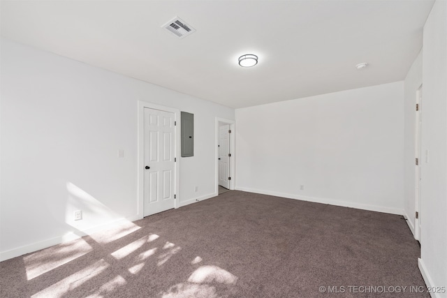 carpeted spare room featuring baseboards, electric panel, and visible vents