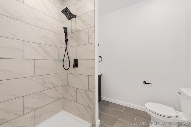 bathroom with tile patterned floors, baseboards, a tile shower, and toilet