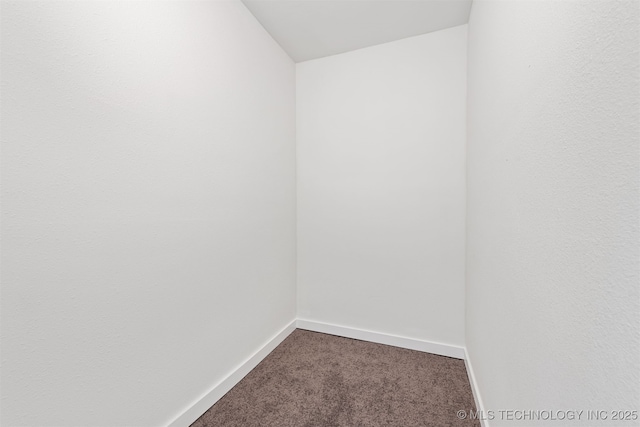 unfurnished room featuring baseboards and dark colored carpet