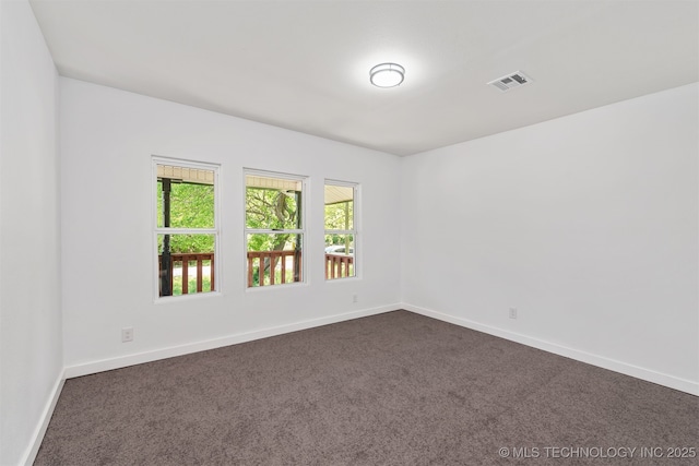 unfurnished room featuring visible vents, baseboards, and dark carpet