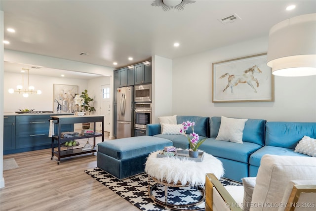 living area with visible vents, recessed lighting, light wood finished floors, and an inviting chandelier