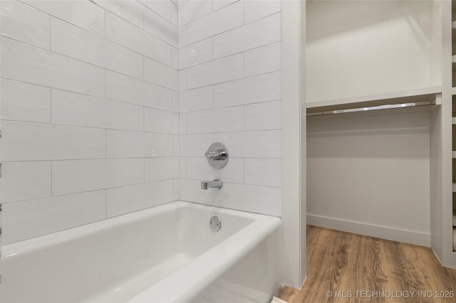 bathroom featuring baseboards, bathtub / shower combination, and wood finished floors