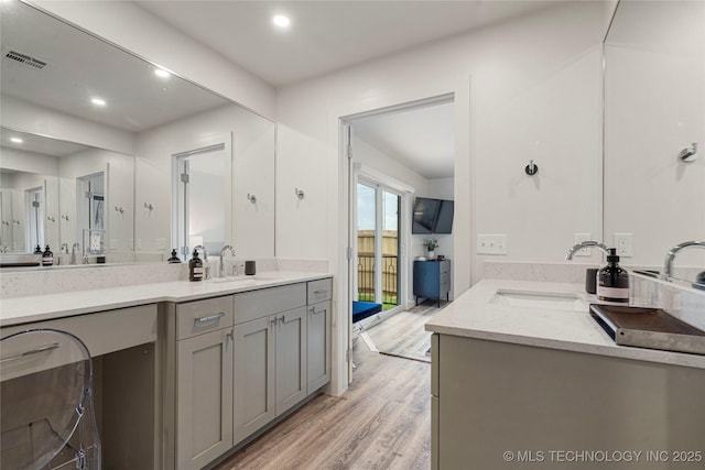 full bath featuring visible vents, a sink, wood finished floors, and two vanities