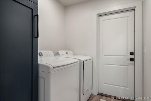 laundry room featuring laundry area, washing machine and dryer, and wood finished floors