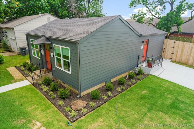 view of home's exterior with a yard, fence, and roof with shingles