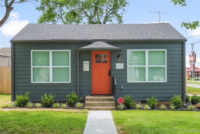 view of front facade with roof with shingles and a front yard