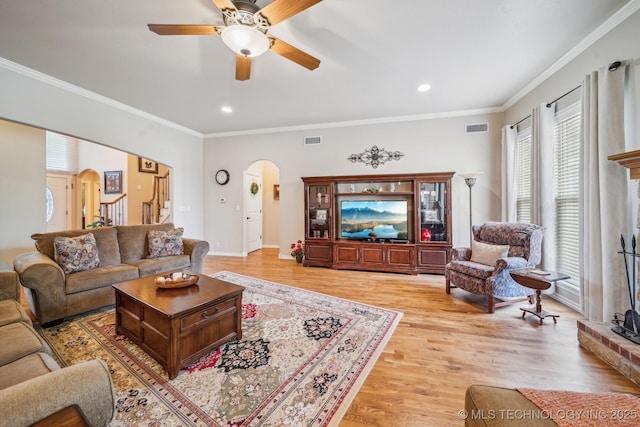 living room featuring visible vents, arched walkways, a ceiling fan, and light wood-type flooring